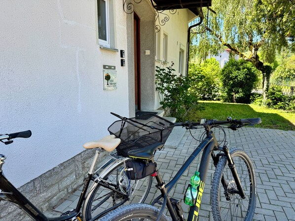 A bicycle parked on a paved area next to a building with a white wall and a window.
