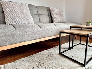 A modern living room with a grey sofa, a wooden coffee table, and a patterned rug.