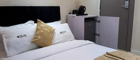 A hotel room with a bed, a wardrobe, a coffee maker, and a door.