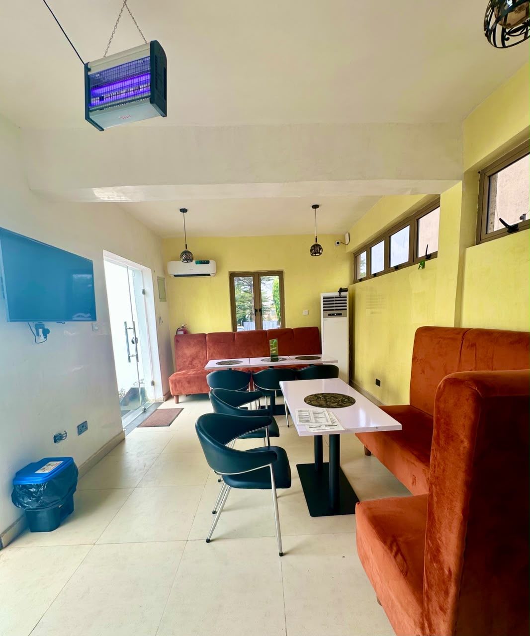 Un comedor con mesa y sillas, un sofá y un proyector instalado en el techo.