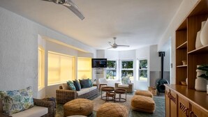 Un soggiorno moderno con mobili in vimini, una televisione a schermo piatto e una ventola a soffitto.