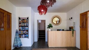 A reception area with a bulletin board, a reception desk, a staircase, and a plant. - Cape Agulhas Guesthouse (L'Agulhas)