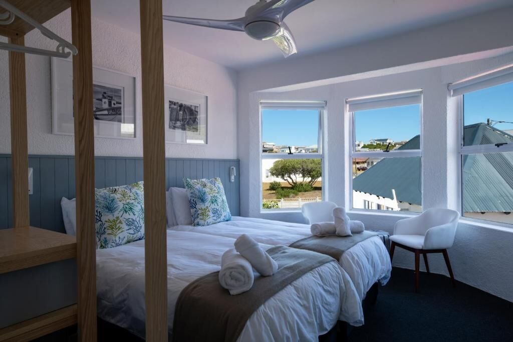 A hotel room with two beds, a large window, and a view of the outside.