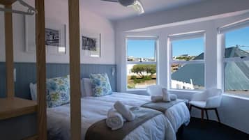 A hotel room with two beds, a large window, and a view of the outside.