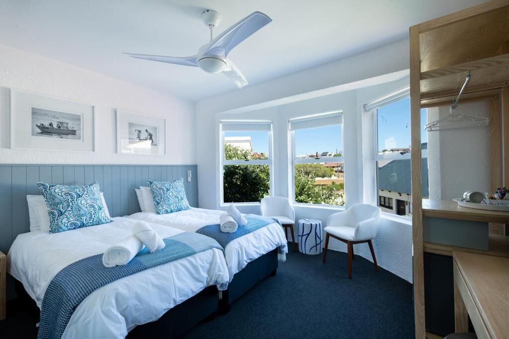Habitación de hotel con cama, dos sillas, escritorio y vista al exterior.