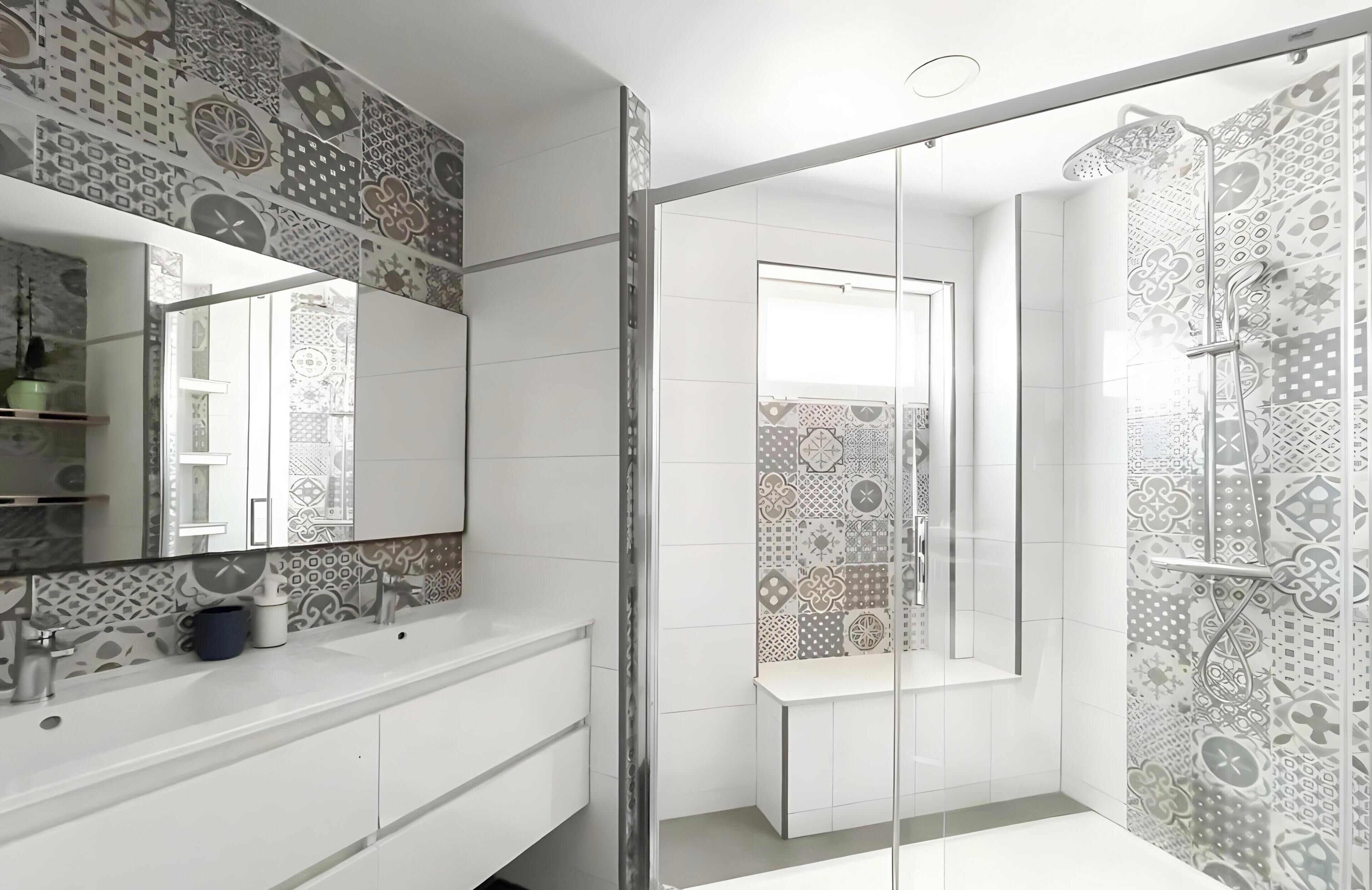 Een moderne badkamer met een glazen douchecabine, een grote spiegel en betegelde vloeren.