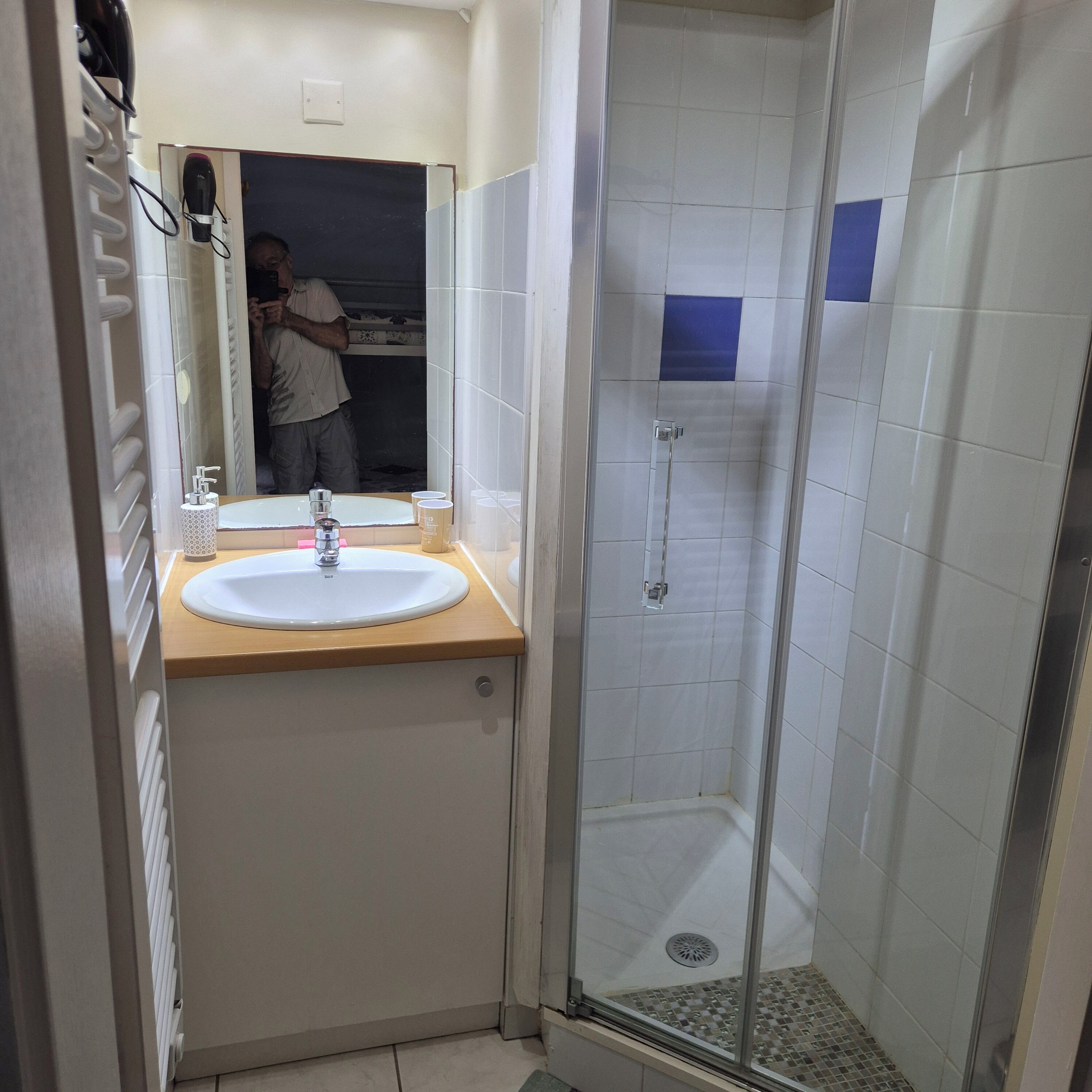 Ein Badezimmer mit Waschbecken, Spiegel und einer Duschkabine.