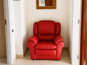 A red leather chair in a room with white walls and a framed picture above it. - Historic Stay Near the Sassi of Matera (Matera)
