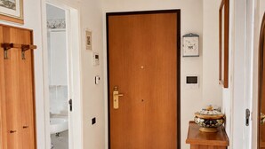 A hallway with a wooden door, a white sink, and a small cabinet with a decorative item on top. - Historic Stay Near the Sassi of Matera (Matera)