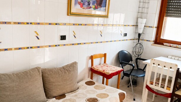 A room with a sofa, a dining table with chairs, a small table with a red tablecloth, and a picture on the wall. - Historic Stay Near the Sassi of Matera (Matera)