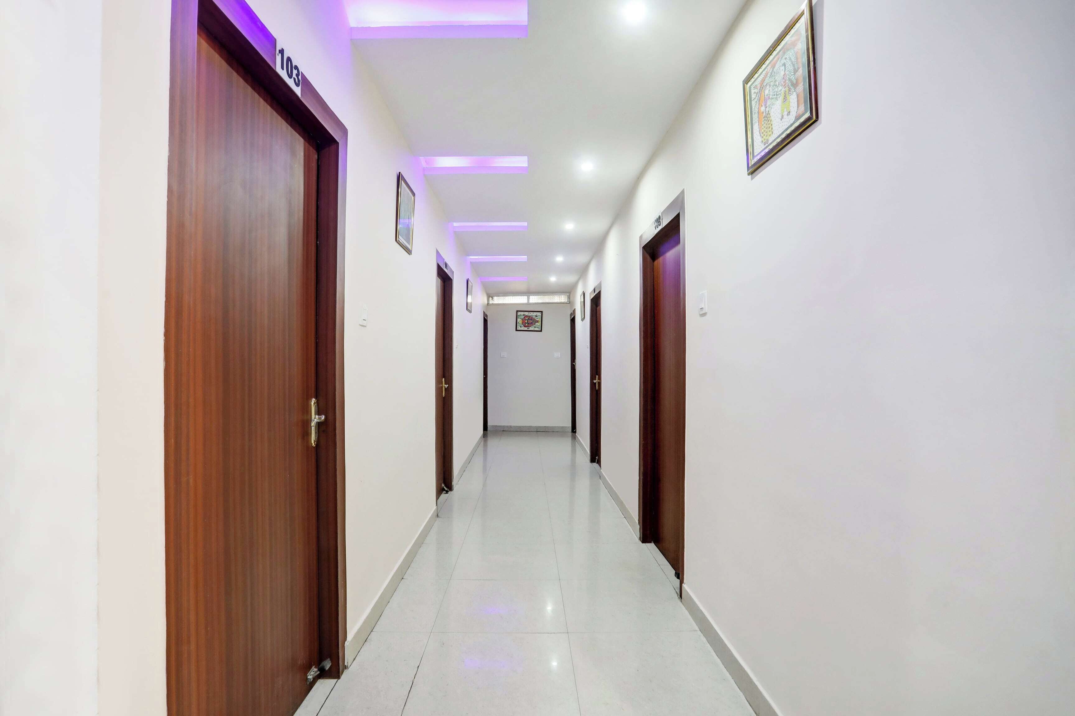 A hallway with wooden doors, numbered 103 and 108, and a framed picture on the wall.
