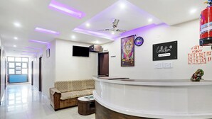 Et receptionområde med en sofa, et fjernsyn, et ur og et skilt, der viser etagenummeret.