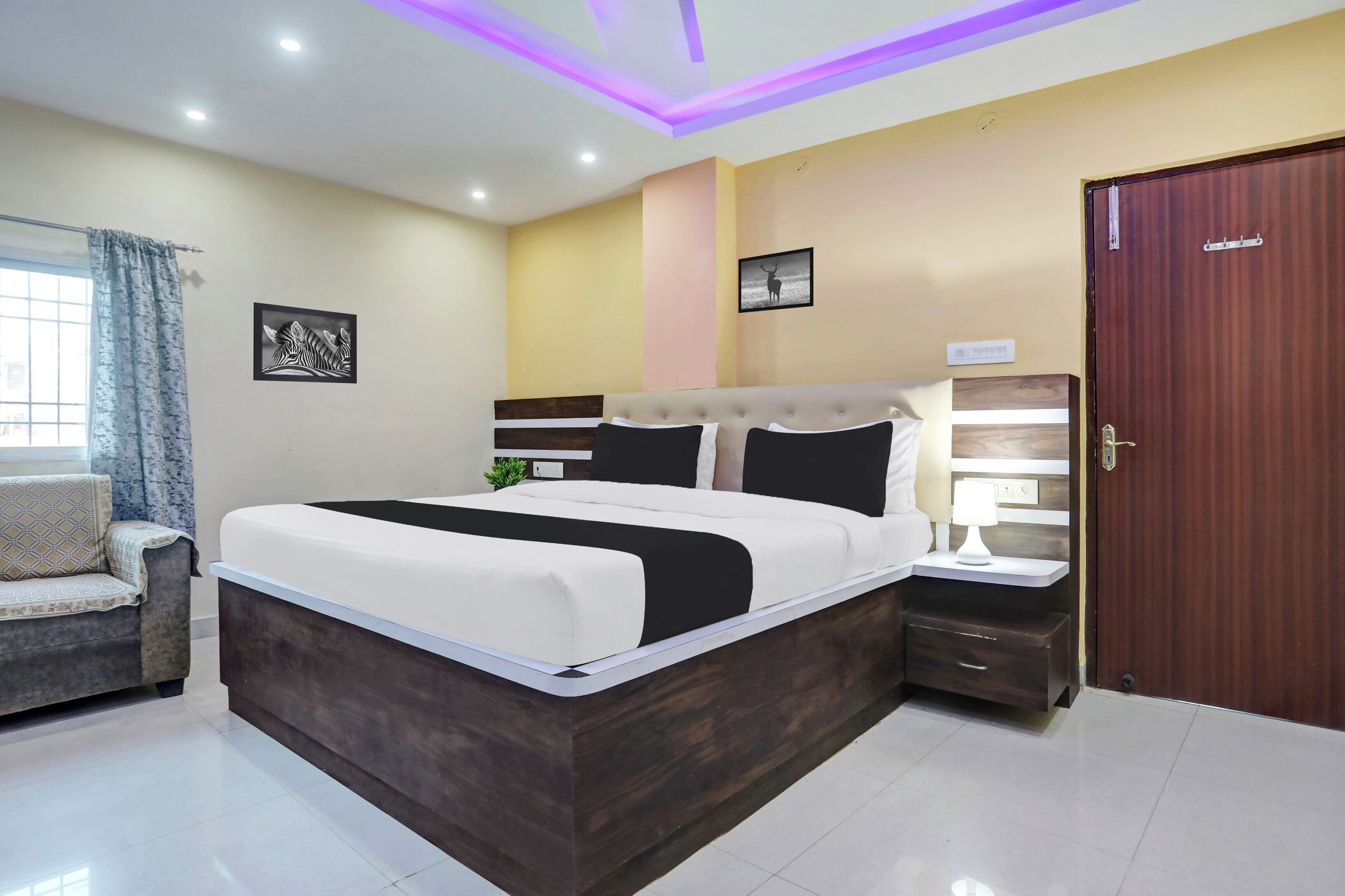 Un dormitorio con cama, mesitas de noche, armario y ventana con cortinas.