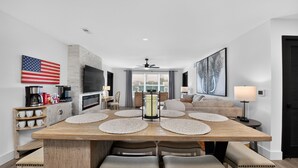 Una sala de estar moderna con comedor, chimenea y un ventanal grande.
