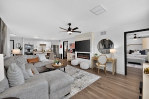 A modern living room with a grey sofa, a coffee table, and a fireplace. - Bama Oasis | 3 Private Suites | Pool & Fitness Center (Tuscaloosa)