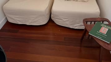 Una habitación pequeña y acogedora con dos sillones beige, una silla de madera y una mesita con un libro.