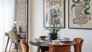 A dining area with a round table set for two, surrounded by chairs, with artwork on the wall and a potted plant on the table. - Urban Rest Albert Embankment (London)