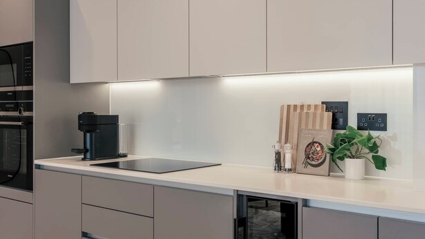 A modern kitchen with a built-in coffee machine, a glass cabinet, and a potted plant. - Urban Rest Albert Embankment (London)