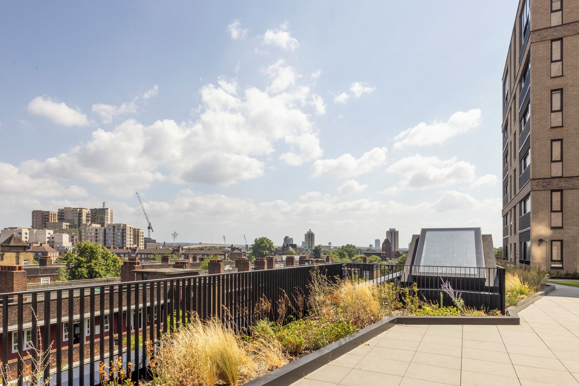 A rooftop terrace with a view of the city skyline, including various buildings and a river.