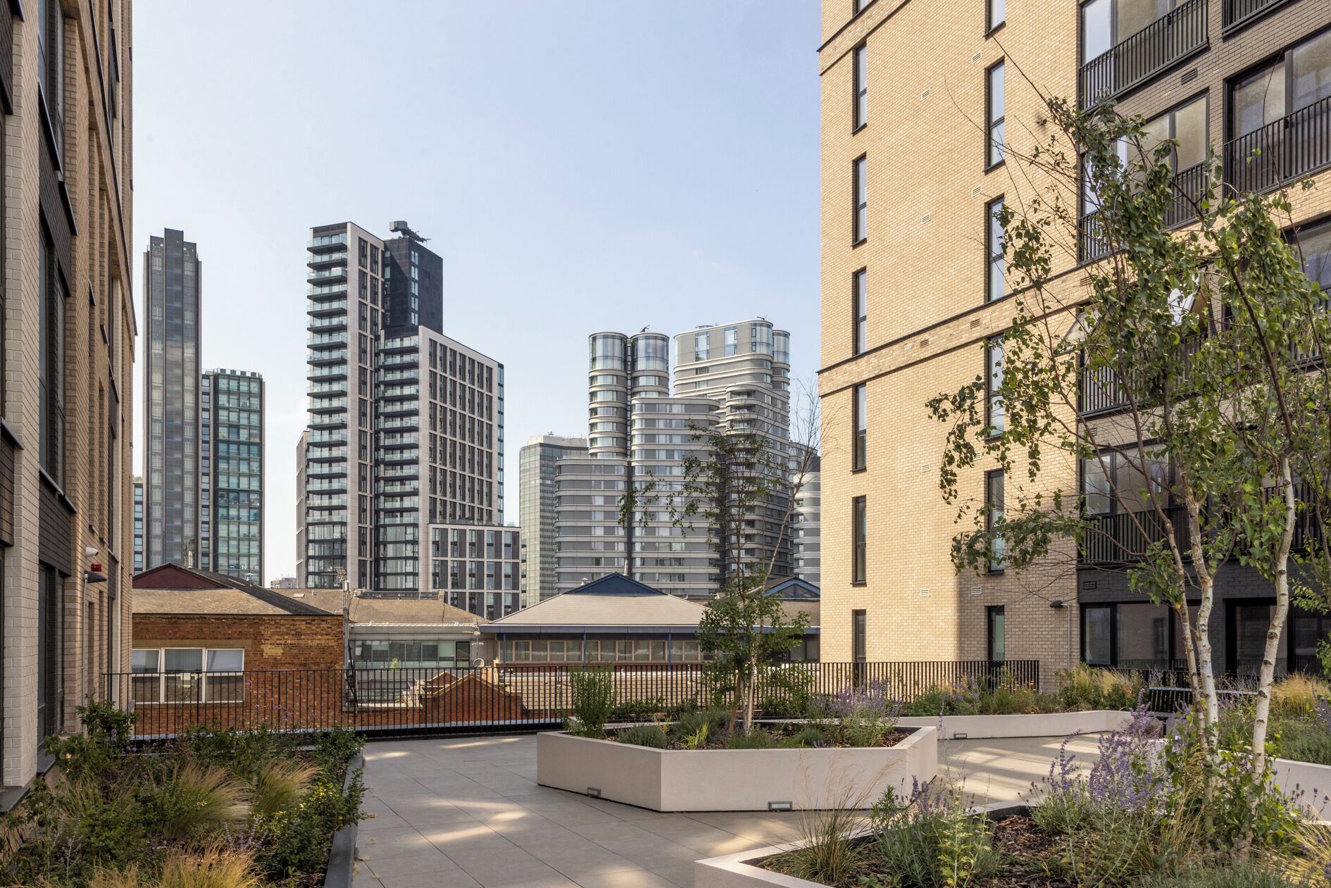 A residential area with modern buildings, a gated entrance, and a landscaped courtyard.