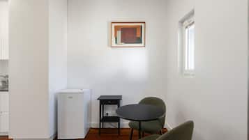 Una cocina compacta con un refrigerador, una mesita y dos sillas.