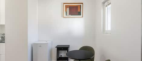 Une cuisine de taille réduite, équipée d’un réfrigérateur, d’une petite table et de deux chaises.
