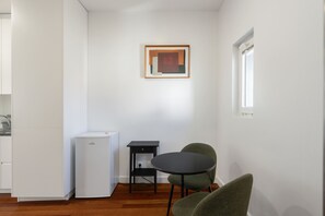 Una cocina compacta con un refrigerador, una mesita y dos sillas.