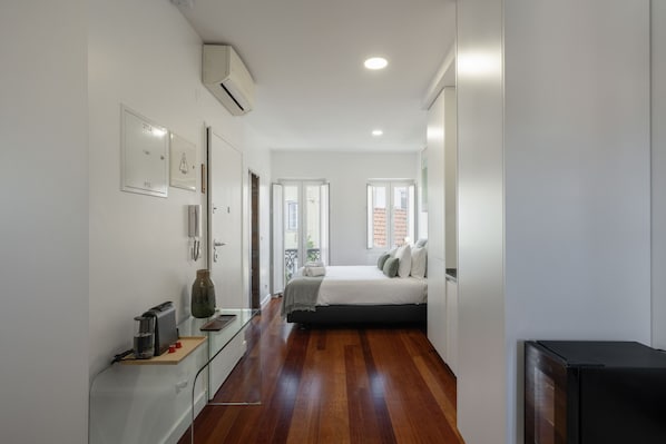 Un dormitorio moderno con cama, mesitas de noche, cómoda y un gran ventanal.