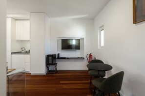 Un espacio habitable moderno y funcional con cocina, comedor y un televisor de pantalla plana montado.