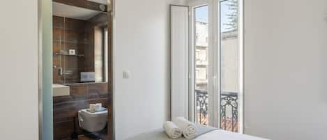 Una habitación de hotel con cama, baño y balcón con vistas.