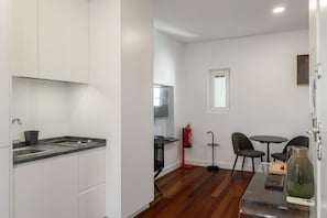 Una cocina compacta con armarios blancos, encimera de granito y horno integrado.