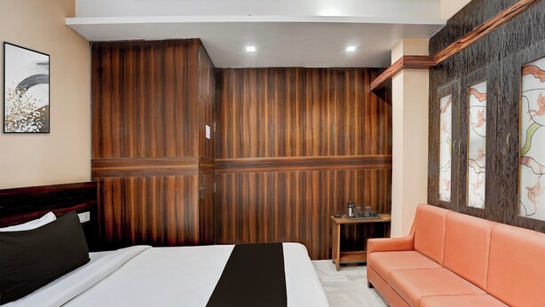 Une chambre d’hôtel avec un lit, un canapé, une petite table avec un plateau, et un mur recouvert de panneaux en bois.