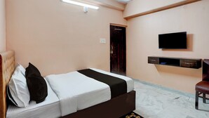 Una habitación de hotel con una cama, un televisor montado en la pared y un escritorio pequeño con cajones.