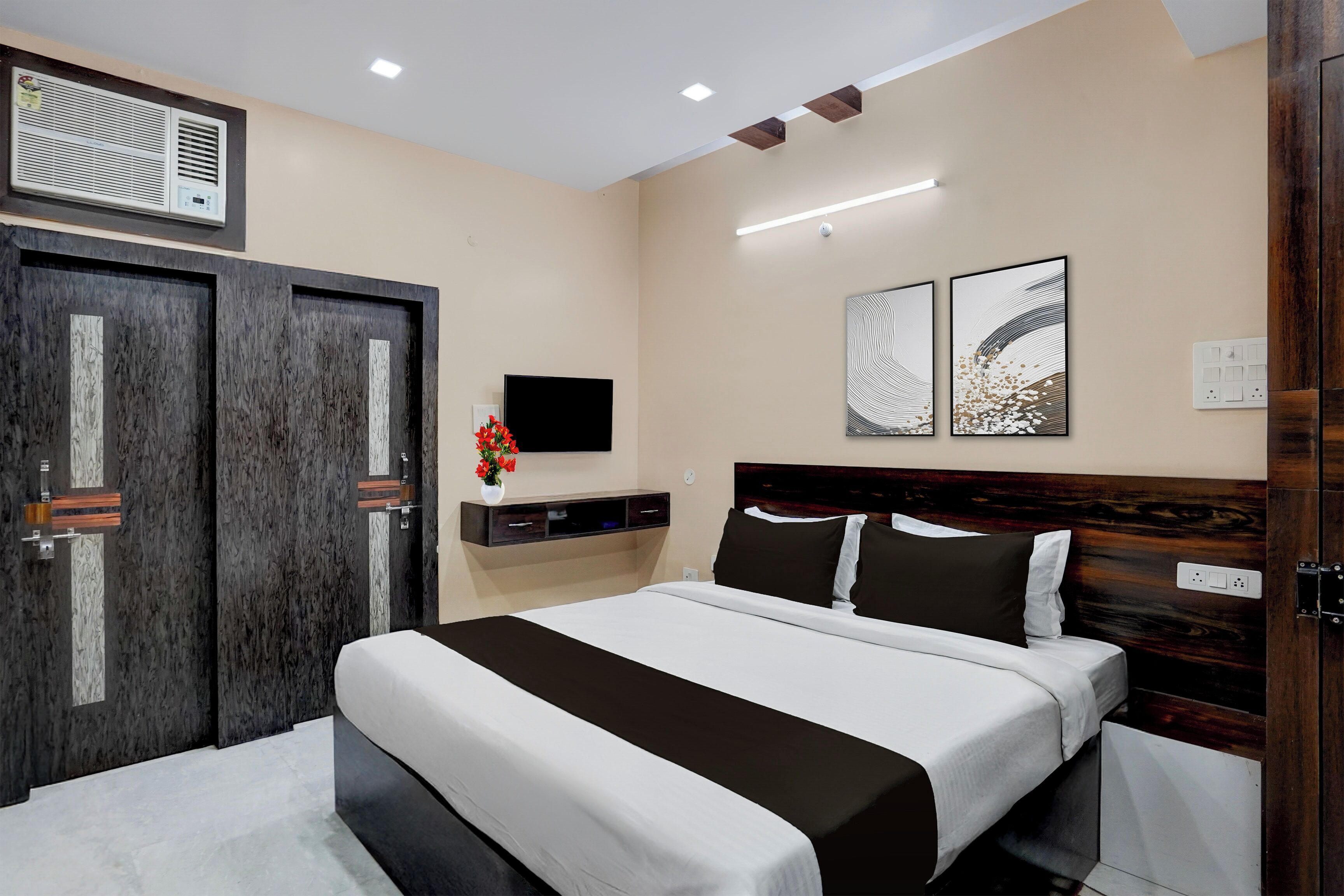Habitación de hotel con cama, televisor, estante en la pared y una puerta.