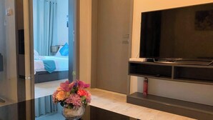 A hotel room with a bed, a TV, and a vase of flowers on the counter. - Pattaya Central I Near The Beach I Nice Pool (Pattaya)