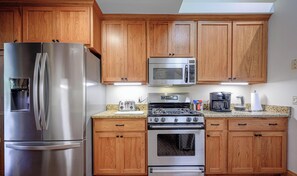 A kitchen with wooden cabinets, stainless steel appliances including a refrigerator, microwave, and oven, and a granite countertop. - King Bed: Deck w/Grill: Fireplace: Smart TVs: Pool + Gym Access: EV Level 2 (Galena)