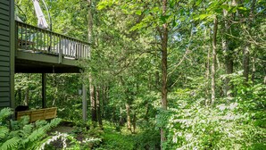 A wooden deck with a railing overlooking a dense forest. - King Bed: Deck w/Grill: Fireplace: Smart TVs: Pool + Gym Access: EV Level 2 (Galena)