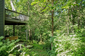 Eine Holzterrasse mit Geländer, mit Blick auf einen dichten Wald.