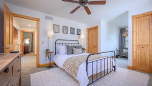 A bedroom with a bed, a ceiling fan, wooden doors, and a window with curtains. - King Bed: Deck w/Grill: Fireplace: Smart TVs: Pool + Gym Access: EV Level 2 (Galena)