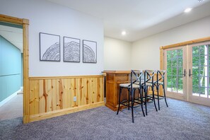 Ein Zimmer mit einer holzverkleideten Wand, einem Essbereich mit Tisch und Stühlen sowie einem großen Fenster mit Blick auf Grünflächen.