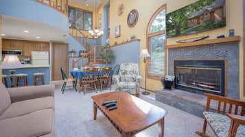 A spacious living room with a fireplace, a dining area with a table and chairs, and a kitchen area with a microwave and refrigerator.