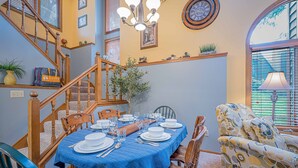 Comedor con mantel azul, sillas de madera y una araña.