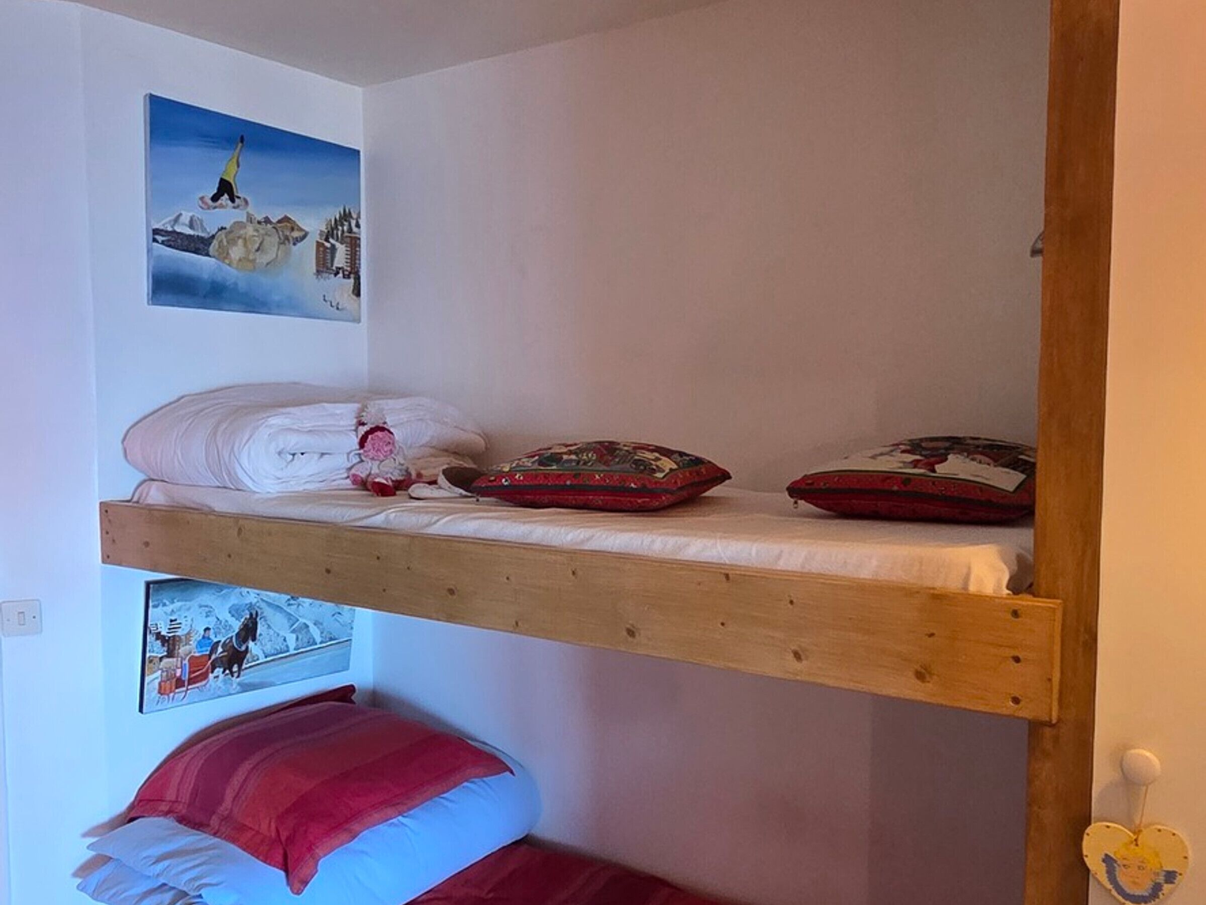 Un lit superposé avec une structure en bois, un oreiller et une couverture sur le lit du haut.