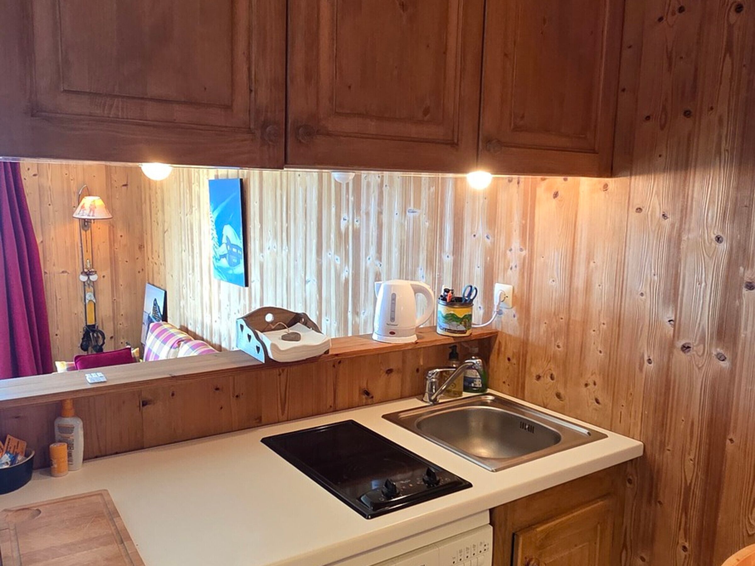 Une cuisine de taille réduite, dotée de meubles de rangement en bois, d’un évier, d’une cuisinière et d’un plan de travail.