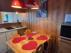 A wooden interior with a kitchen area, a dining table with heart-shaped placemats, and a painting on the wall. - Apartment with great view, 4 guests (Avoriaz)