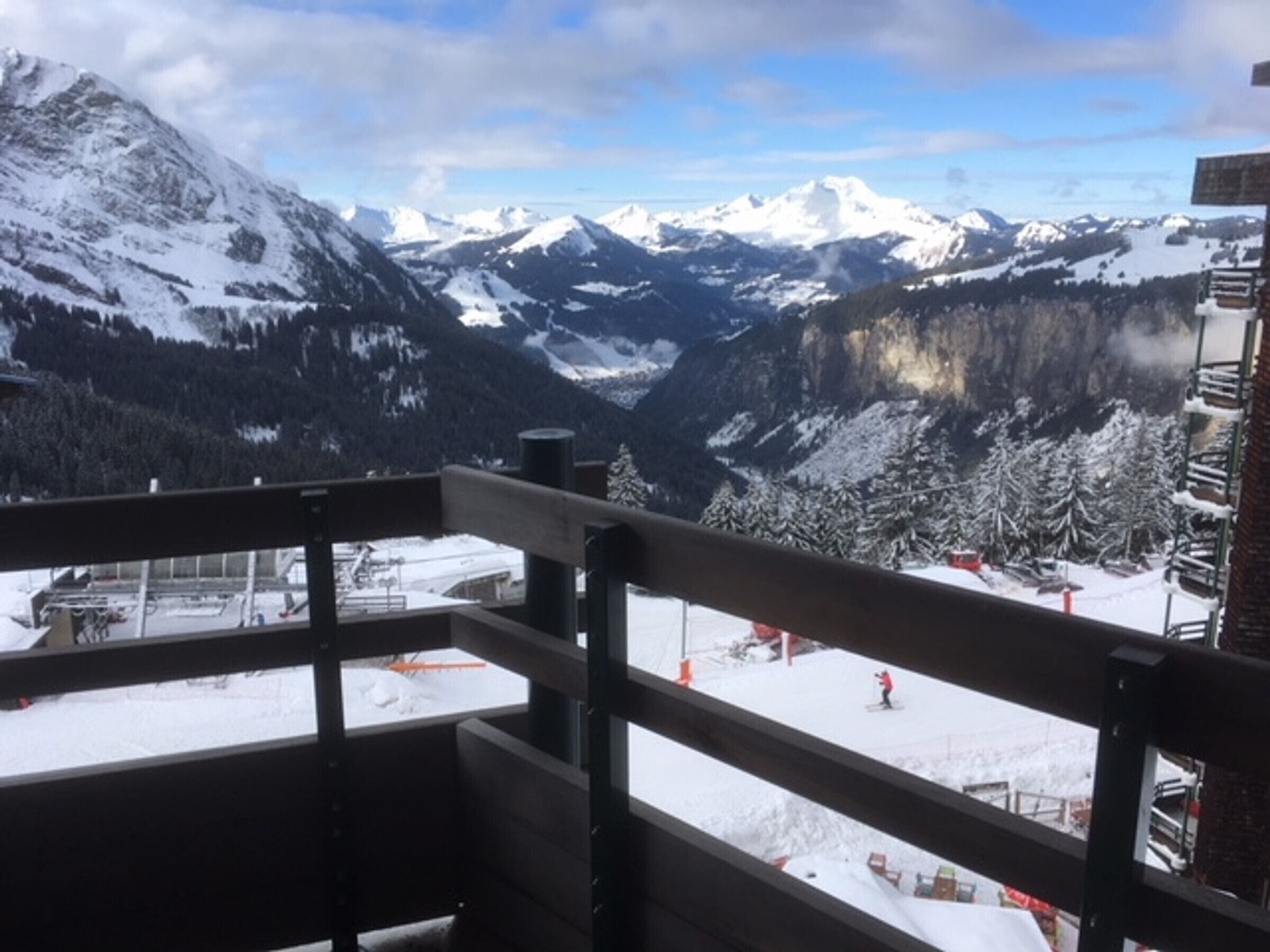 A mountain view from a balcony with snow-covered slopes and a clear sky.