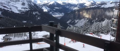 A mountain view from a balcony with snow-covered slopes and a clear sky.