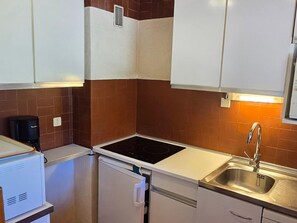 A compact kitchen with a built-in stove, a sink, and a coffee maker. - Avoriazien style apartment with view - 6 guests (Avoriaz)