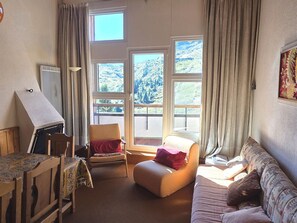 A room with a table, two chairs, a sofa, and a window with a view of mountains. - Avoriazien style apartment with view - 6 guests (Avoriaz)