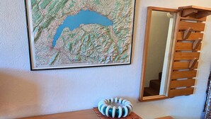 A room with a wooden desk, a chair, a small round stool, a decorative object on the desk, a map on the wall, and a mirror with a wooden frame. - Avoriazien style apartment with view - 6 guests (Avoriaz)